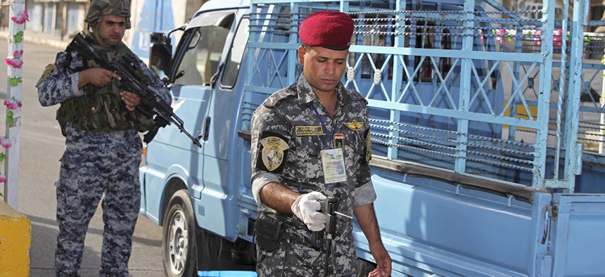 Iraqi policemen check out a vehicle at a checkpoint in central Baghdad, Iraq, Thursday, Sept. 9, 2010. Officer at right is using a bomb detector.