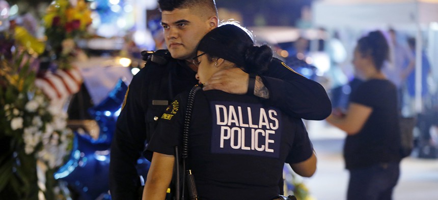 Dallas police officers comfort each other Friday, July 8, 2016, in Dallas in front of police cars decorated as a public memorial in front of police headquarters, in honor of Dallas police who were killed Thursday.