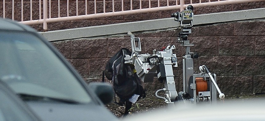 Nashville Metro Police Bomb Squad robot picks up a backpack on the side of a movie theater following a shooting, Wednesday, Aug. 5, 2015, in Antioch, Tenn.