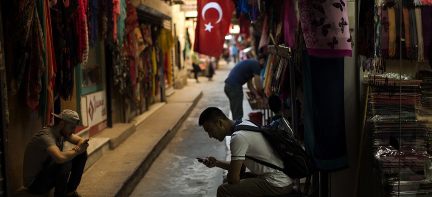 Sellers wait for customers as they look at their phones in central Istanbul, Monday, July 18, 2016. 