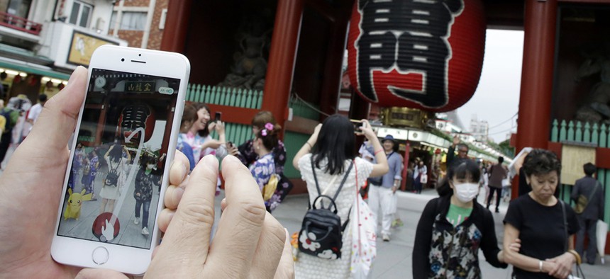 A man tries to catch a Pikachu, a Pokemon character, while he plays "Pokemon Go" in front of Kaminarimon, or Thunder Gate, at the Sensoji temple in Tokyo.