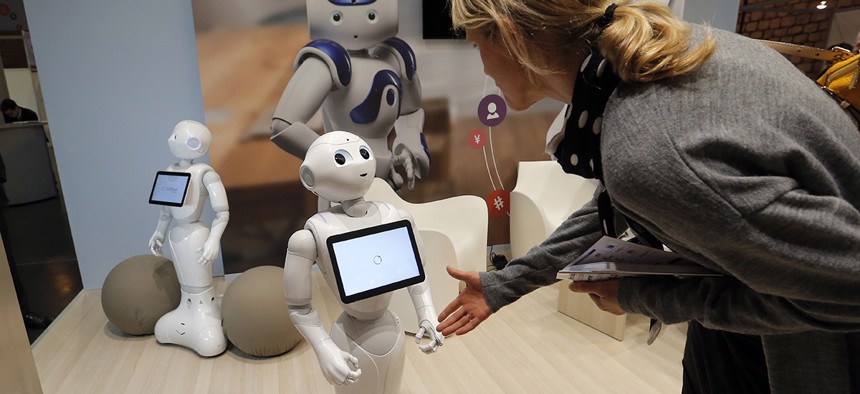 Engineer consultant Valerie Hawley, right, tries to shake hands with Pepper the robot of Softbank Robotics Europe.
