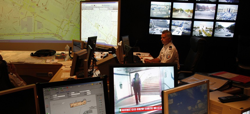 French Police officer checks on video monitors and computer screens in the underground security central command center of the Paris prefecture