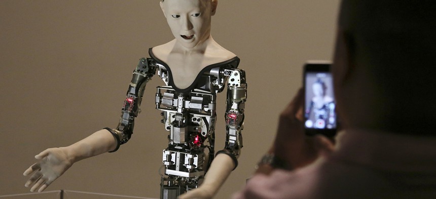 A visitor takes photos of the humanoid robot "Alter" displayed at the National Museum of Emerging Science and Innovation in Tokyo, Monday, Aug. 1, 2016.