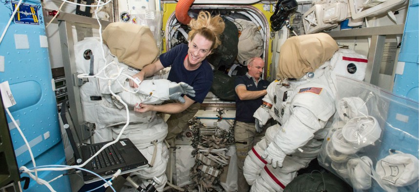 Expedition 48 crew members Kate Rubins (left) and Jeff Williams (right) of NASA outfit spacesuits inside of the Quest airlock aboard the International Space Station.