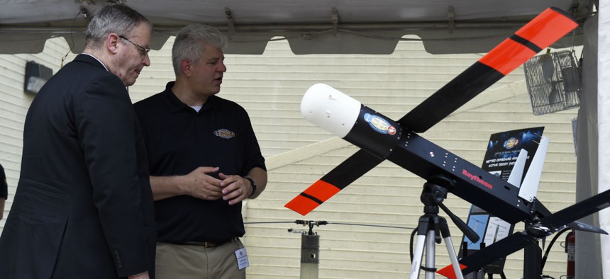An Office of Naval Research program officer shows Deputy Secretary of Defense Robert Work a LOCUST prototype.