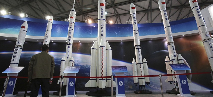 A visitor looks at the scale models of Chinese space rockets displayed at the China International Industry Fair in Shanghai, China.