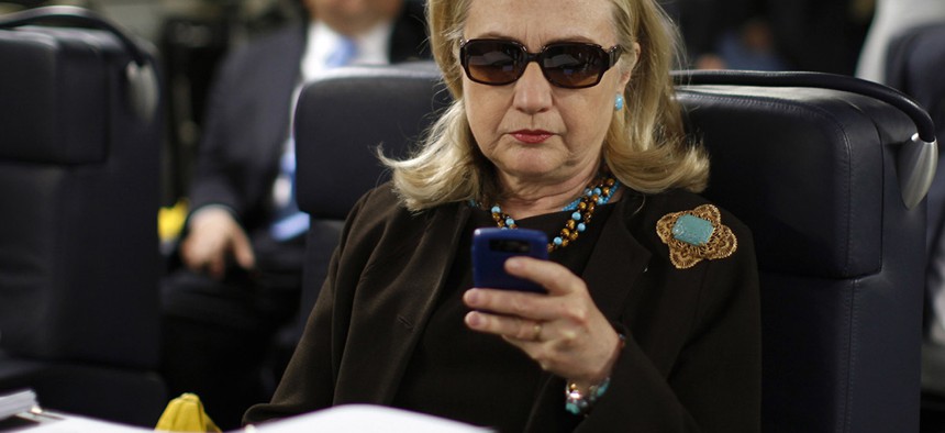 Then-Secretary of State Hillary Rodham Clinton checks her Blackberry from a desk inside a C-17 military plane.