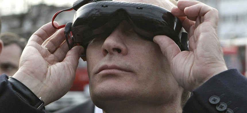 Russian Prime Minister Vladimir Putin tests goggles with an electronic connection that allows him to see the view from an unmanned drone aircraft.