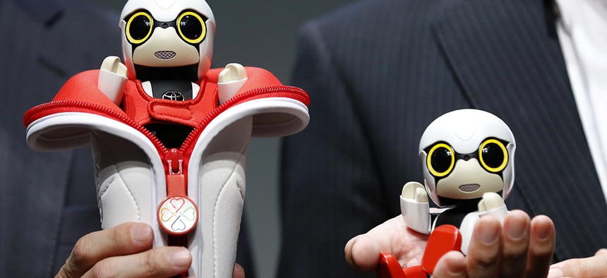 Toyota Motor Corp. SMO Moritaka Yoshida, right, and Fuminori Kataoka, project general manager from Toyota Motor Corp., pose for photographers with compact sized humanoid communication robots, Kirobo Mini, during a press unveiling in Tokyo.