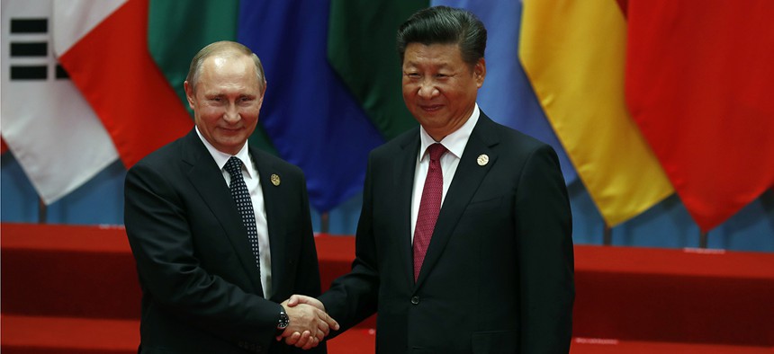 Russian President Vladimir Putin, left, shakes hands with Chinese President Xi Jinping.