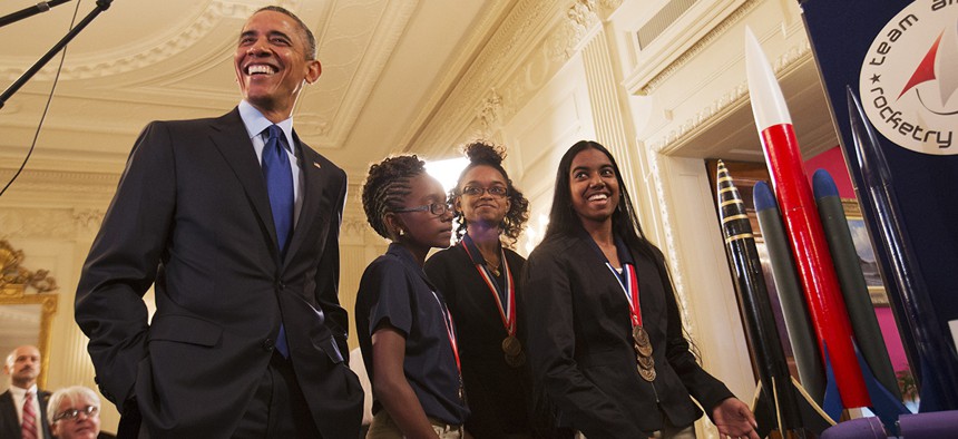 President Barack Obama laughs as Stephanie Bullock, 15, of Saint Croix, Virgin Islands, far right, explains her team's rocket design during the president's tour of the White House Science Fair, Monday, March 23, 2015.