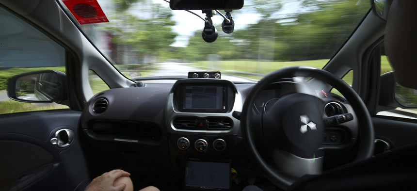 A driver, right, gets his hands off of the steering wheel of an autonomous vehicle during its test drive in Singapore.