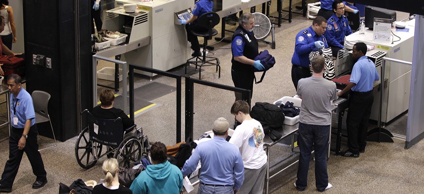 Travelers at Seattle-Tacoma International Airport undergo luggage security screening at a TSA checkpoint.