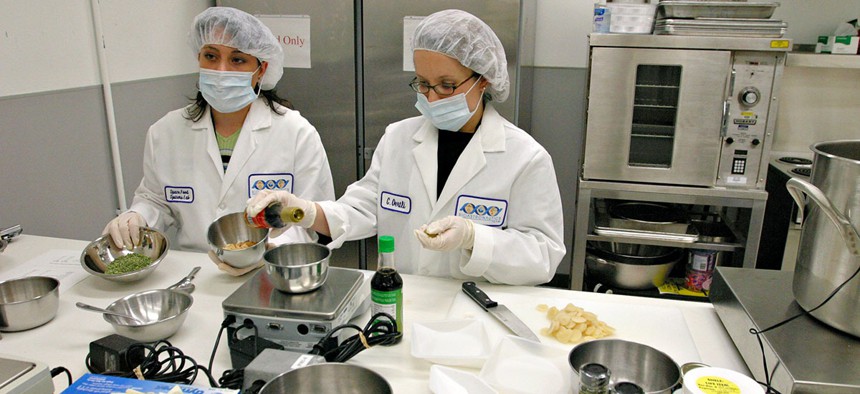 NASA Food Scientists Donna Nabors, left, and Connie Oertli, right, demonstrate how they prepare freeze dried fried rice in the Space Food Systems Laboratory at Johnson Space Center in Texas.