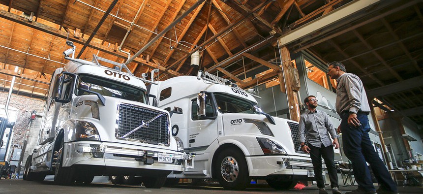 Employees stand next to self-driving, big-rig trucks during a demonstration at the Otto headquarters, in San Francisco.