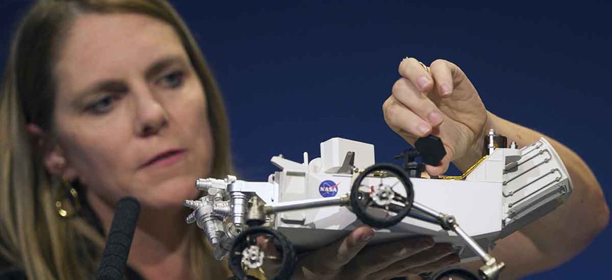 Jennifer Trosper, Mars Science Laboratory, MSL mission manager, JPL, adjusts the high-gain antenna on a rover model during a news briefing on the last data and imagery from Sol 1 at NASA's Jet Propulsion Laboratory.