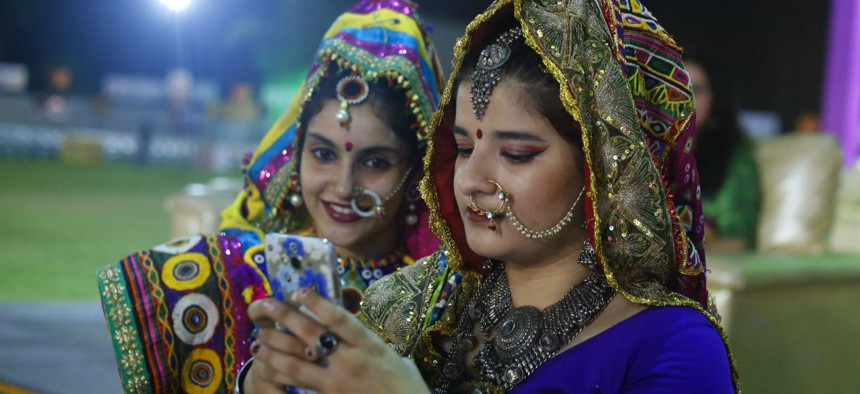 Indian girls in traditional attire, check a mobile phone after performing Garba, a traditional dance of Gujarat state on the first night of Hindu festival Navratri in Ahmadabad.