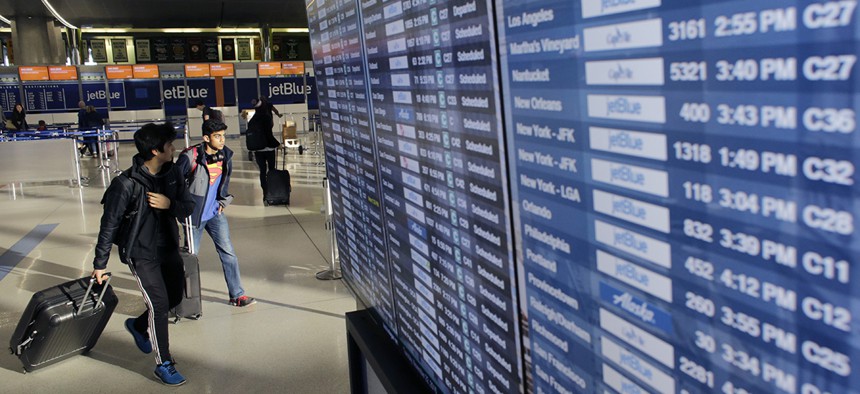 Travelers walk past an airline reader board Tuesday, Nov. 22, 2016, at Logan International Airport, in Boston.