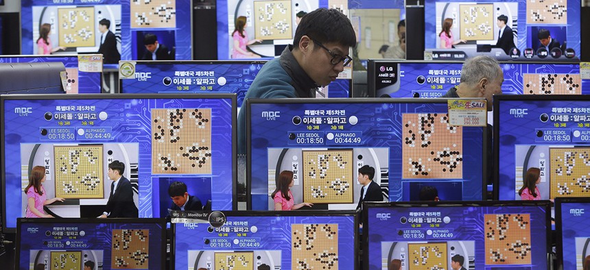 TV screens show the live broadcast of the Google DeepMind Challenge Match between Google's artificial intelligence program, AlphaGo, and South Korean professional Go player Lee Sedol.
