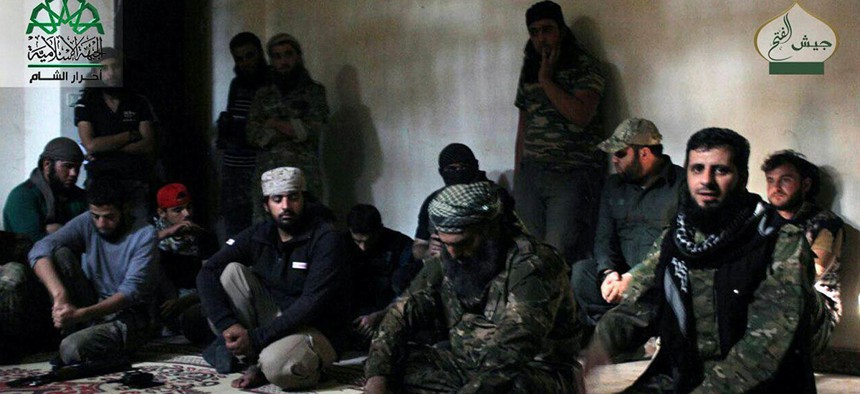 In this photo posted Oct. 30, 2016, by the Syrian militant group Ahrar al-Sham, shows the general commander of Ahrar al-sham, Mohannad al-Masri, center, visiting fighters in rural western Aleppo, Syria.