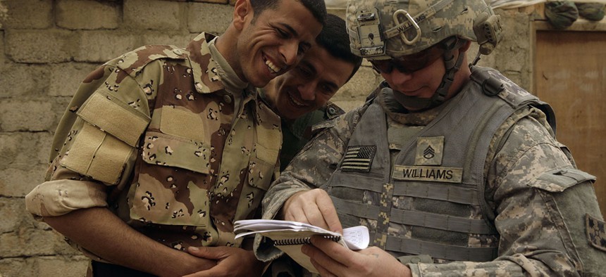 Iraqi Army soldiers look at a book of Arabic phrases as U.S. Army Staff Sgt. Robert Williams, 37, assigned to Delta Co., 1st Combined Arms Battalion, 67th Armor Regiment, looks for help in communicating in Mosul.