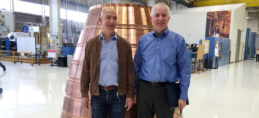Blue Origin founder Jeff Bezos, left, stands with president Rob Meyerson in front of a copper exhaust nozzle to be used on a space ship engine on the company's research and production floor.