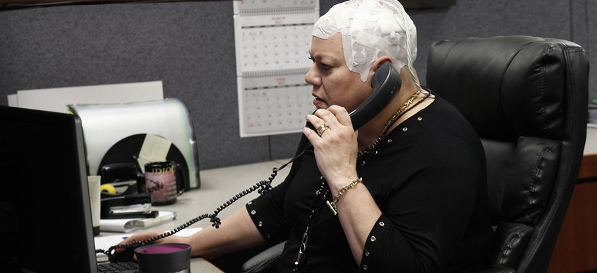 Joyce Endresen wears an Optune therapy device for brain cancer, as she speaks on a phone at work in Aurora, Ill. 