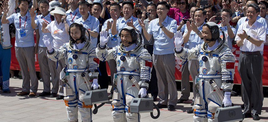 China's astronauts from left, Wang Yaping, Zhang Xiaoguang and Nie Haisheng wave as they leave the Jiuquan satellite launch center near Jiuquan in western China's Gansu province, June 2013.