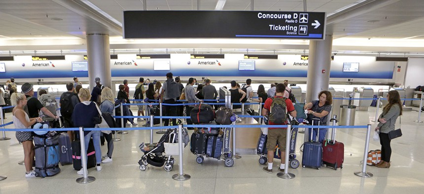 Airline passengers stand in line as they wait to rebook their canceled flight at the American Airlines counter at Miami International Airport, March 13, 2017.
