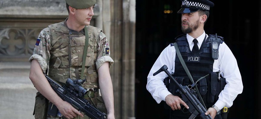 An armed soldier and policeman stand guard at Parliament, in London, Thursday, May 25, 2017. 
