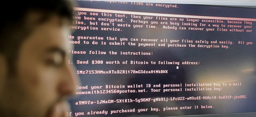 Razvan Muresan, a Bitdefender public relations specialist is backdropped by a screenshot of the message displayed on computers affected by the latest cyberattack, in Bucharest, Romania, Wednesday, June 28, 2017.