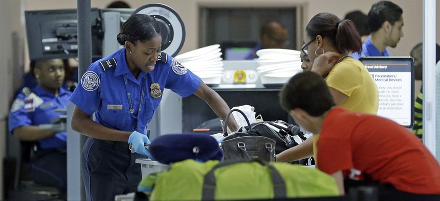 A Transportation Security Administration officer checks travelers luggage to be screened by an x-ray machine at a checkpoint at Fort Lauderdale-Hollywood International Airport, Friday, May 27, 2016.