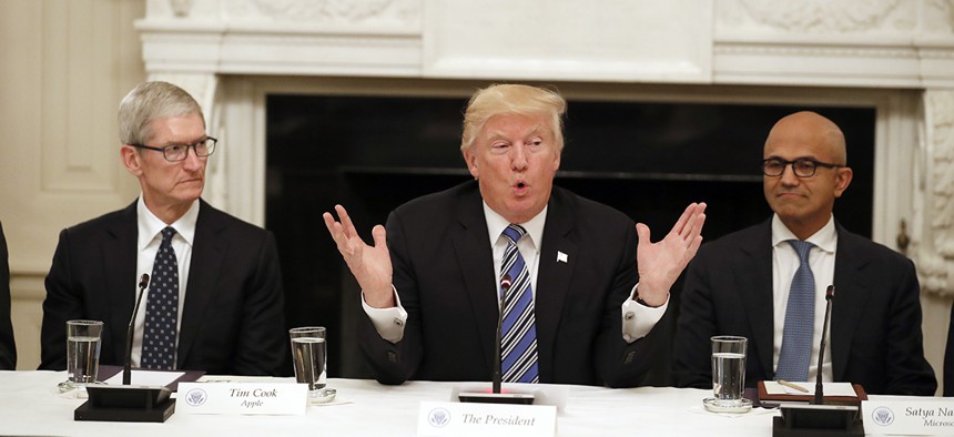 President Donald Trump, center, speaks as he is seated between Tim Cook, Chief Executive Officer of Apple, left, and Satya Nadella, Chief Executive Officer of Microsoft, right, during an American Technology Council roundtable at the White House.