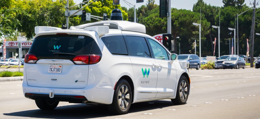 Waymo self-driving car cruising on a street in August.