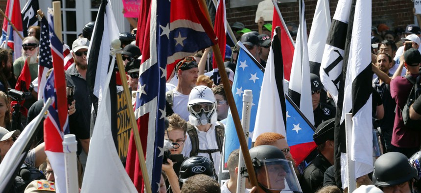 White nationalist demonstrators walk into the entrance of Lee Park surrounded by counter demonstrators in Charlottesville, Va., Saturday, Aug. 12, 2017. 
