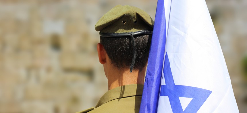 Israeli soldier with flag of Israel on blurred background of Western Wall.