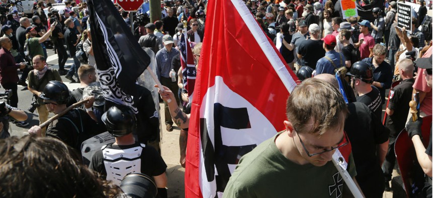 A man carries a Nazi flag into the entrance to Emancipation Park in Charlottesville, Va., Sat. Aug. 12, 2017.