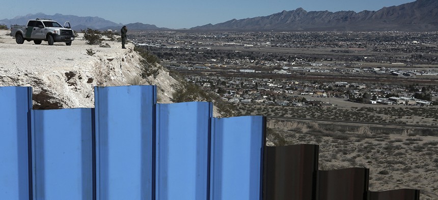 An agent of the border patrol, observes near the Mexico-US border fence, on the Mexican side, separating the towns of Anapra, Mexico and Sunland Park, New Mexico.