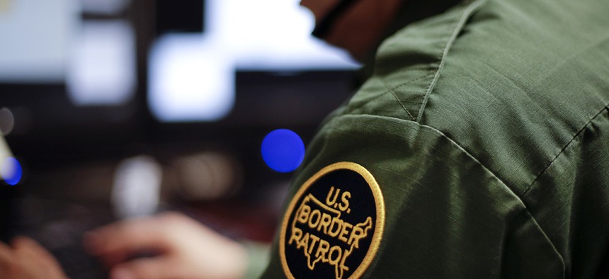A Border Patrol agent uses a headset and computer to conduct a long distance interview by video from a facility in San Diego.