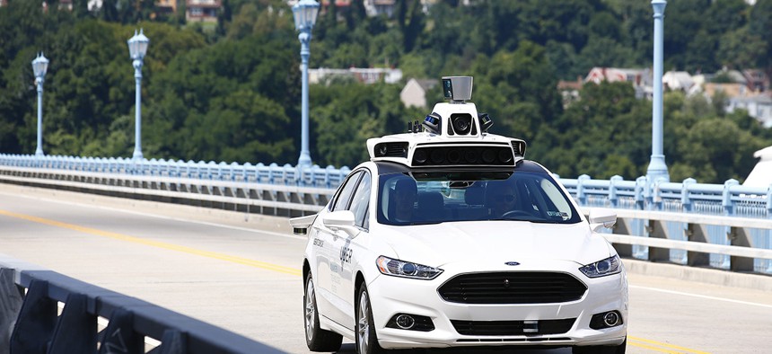 Uber employees test a self-driving Ford Fusion hybrid car, in Pittsburgh.