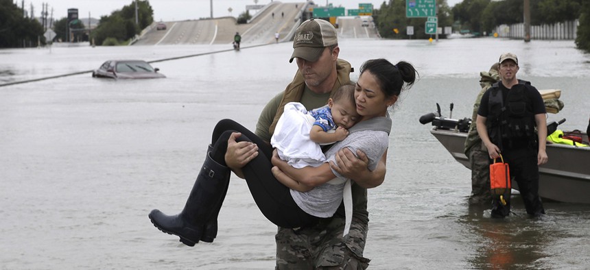 Houston Police SWAT officer Daryl Hudeck carries Catherine Pham and her 13-month-old son Aiden after rescuing them from their home surrounded by floodwaters from Tropical Storm Harvey Sunday, Aug. 27, 2017.