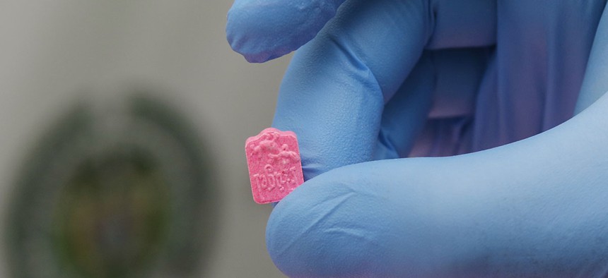 A police officer holds a single MDMA tablet, also known as ecstasy.