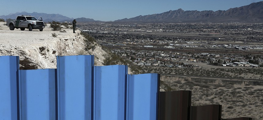 An agent of the border patrol, observes near the Mexico-US border fence, on the Mexican side.