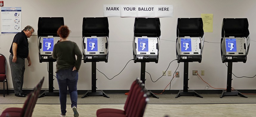 Kelly Monroe, investigator with the Georgia secretary of state office, left, takes a look at a new voting machine being tested at a polling site in Conyers, Ga.