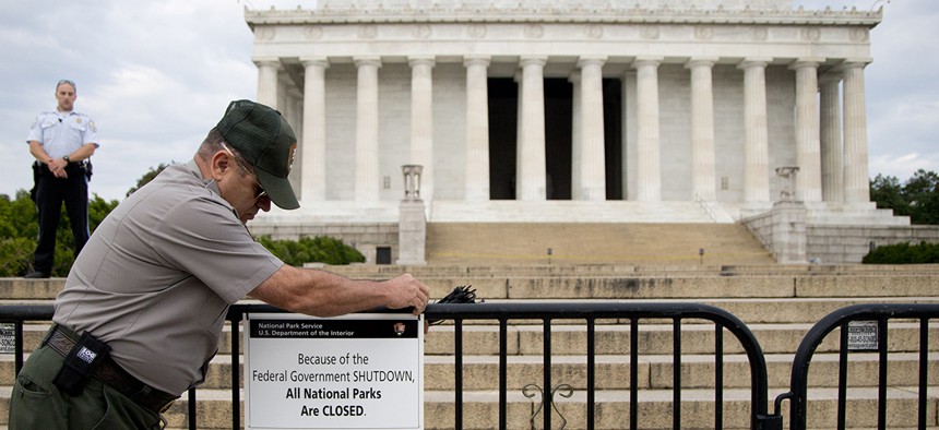 A US Park Police officer watches at left as a National Park Service employee posts a sign on a barricade closing access to the Lincoln Memorial in Washington, Tuesday, Oct. 1, 2013.