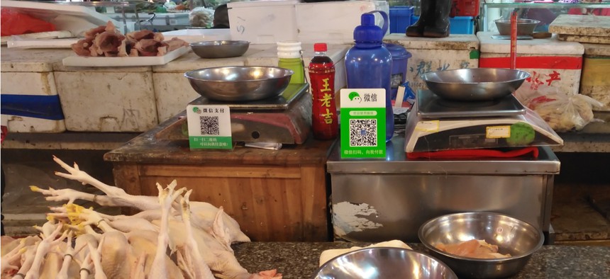 Retailers in a Chinese market use WeChat QR code payment symbols to collect payments.
