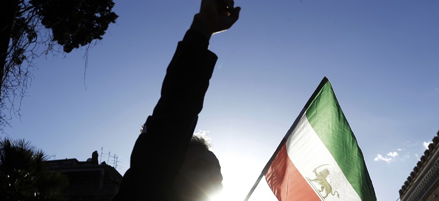 A demonstrator shouts slogans near the flag of the former Imperial State of Iran as he gathers with supporters of Maryam Rajavi, head of the Iranian opposition group National Council of Resistance, outside the Iran Embassy, in Rome, Tuesday, Jan. 2, 2018.
