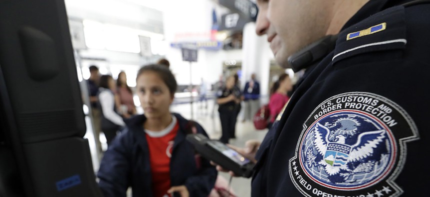 U.S. Customs and Border Protection officer Julio Corro, right, helps a passenger navigate one of the new facial recognition kiosks at a United Airlines gate before boarding a flight to Tokyo, Wednesday, July 12, 2017.