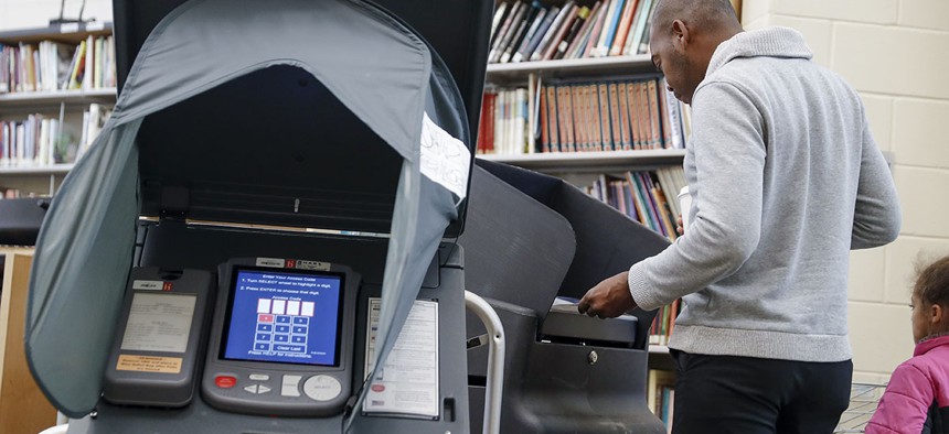 A voter casts his ballot into an electronic voting machine at a polling station in Cincinnati. Ohio.